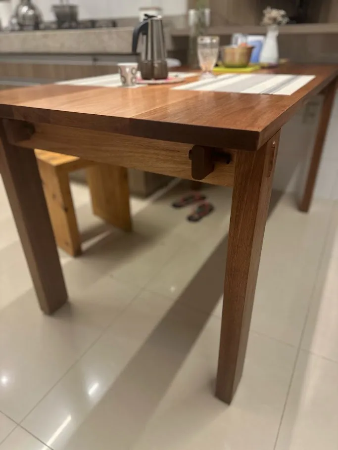 Mesa de cozinha em madeira maciça com quatro pernas e cavilhas aparentes nas travessas, posta com jogo americano e cafeteira italiana. — foto 3