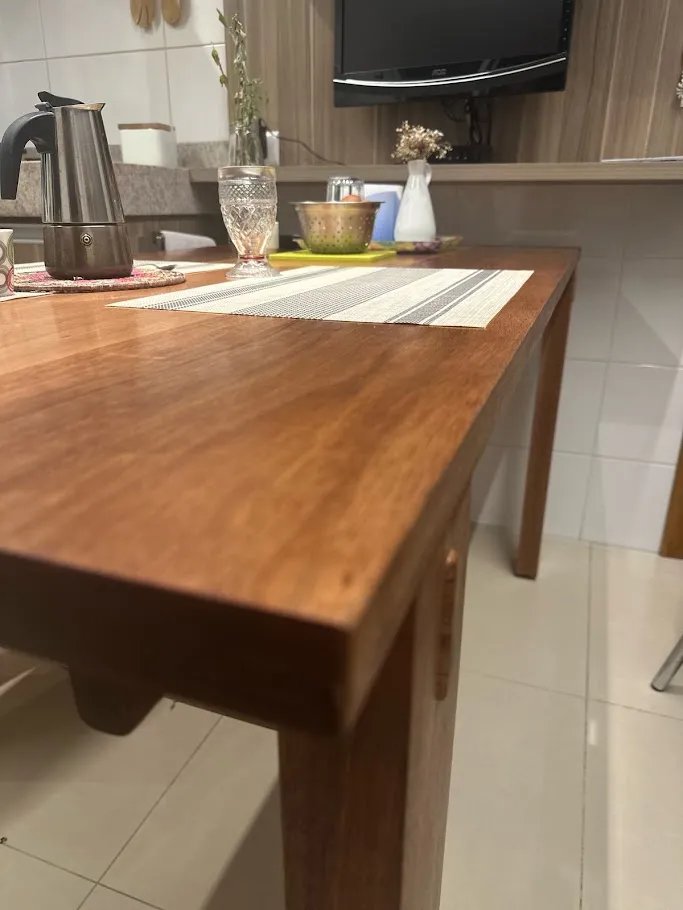 Mesa de cozinha em madeira maciça com quatro pernas e cavilhas aparentes nas travessas, posta com jogo americano e cafeteira italiana. — foto 4