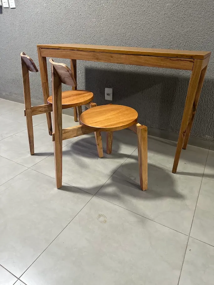 Mesa estreita de madeira maciça encostada na parede de uma cozinha, posta para duas pessoas, com duas cadeiras de assento redondo e encosto curvo. — foto 2